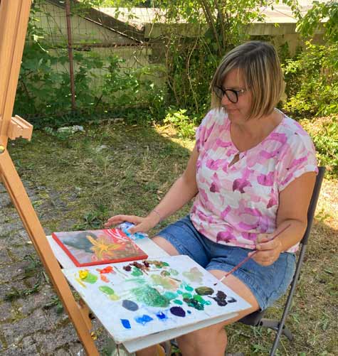 Udeleženka Nine poletne slikarske delavnice  slika v senci stavbe, poletnega ateljeja slikarske delavnice.